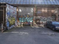 an empty garage filled with graffiti on a brick wall near a parking area with bicycles and a bike