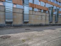 a side walk near a large building with two people walking on the sidewalk behind it