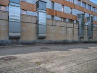 a side walk near a large building with two people walking on the sidewalk behind it