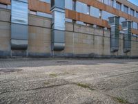 a side walk near a large building with two people walking on the sidewalk behind it