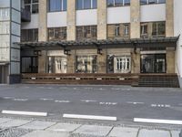 an empty building with signs on the street and people on bikes in traffic passing by