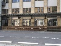 an empty building with signs on the street and people on bikes in traffic passing by