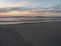 a beach area next to an ocean with a lot of water and clouds above it