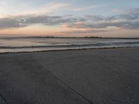 a beach area next to an ocean with a lot of water and clouds above it