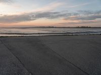 a beach area next to an ocean with a lot of water and clouds above it