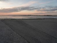 a beach area next to an ocean with a lot of water and clouds above it