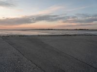 a beach area next to an ocean with a lot of water and clouds above it