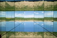 two pictures of a field with a body of water in it and the sky reflected by glass windows