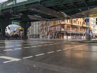 a bridge crosses over an empty city street on a rainy day and people are walking