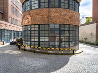 an old brick building is surrounded by black and yellow barriers on the street side of it