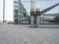 two poles in a city near some buildings and a clock tower in the background is a glass building