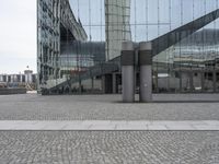 two poles in a city near some buildings and a clock tower in the background is a glass building