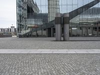 two poles in a city near some buildings and a clock tower in the background is a glass building