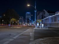 an empty city street is lit up at night with traffic going by, which is the same distance as a street light