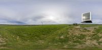 a large field with a mirror on top of it over looking the sky and ground