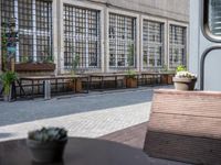 this is an old building with chairs and plants on it's patio table and two wooden benches