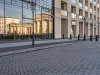 people walking on sidewalk in front of an old hotel building with large windows and doors