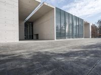 an empty stone floor in front of a building with an open window and some trees