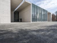 an empty stone floor in front of a building with an open window and some trees