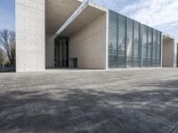 an empty stone floor in front of a building with an open window and some trees