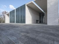 an empty stone floor in front of a building with an open window and some trees