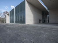 an empty stone floor in front of a building with an open window and some trees