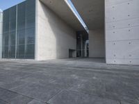 an empty stone floor in front of a building with an open window and some trees
