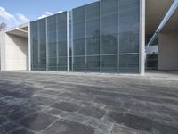an empty stone floor in front of a building with an open window and some trees
