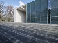 an empty stone floor in front of a building with an open window and some trees