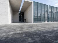 an empty stone floor in front of a building with an open window and some trees