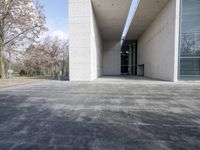 an empty stone floor in front of a building with an open window and some trees