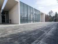 an empty stone floor in front of a building with an open window and some trees