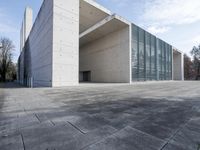 an empty stone floor in front of a building with an open window and some trees