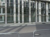 a sidewalk lined with metal steel dividers that create a barrier at the center of a city street