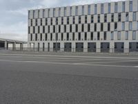 an empty parking lot next to a tall building with multiple stories on the building side