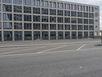 an empty parking lot next to a tall building with multiple stories on the building side