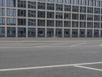 an empty parking lot next to a tall building with multiple stories on the building side