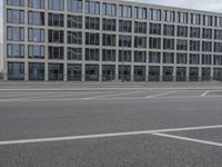 an empty parking lot next to a tall building with multiple stories on the building side