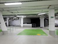 parking spaces with a green area on the far side and white walls to one side