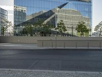 there is an empty street and a huge building reflected in the glass wall behind it