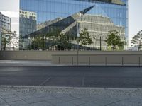 there is an empty street and a huge building reflected in the glass wall behind it