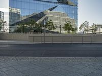 there is an empty street and a huge building reflected in the glass wall behind it