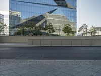 there is an empty street and a huge building reflected in the glass wall behind it