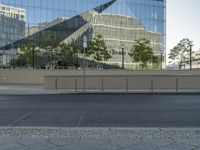 there is an empty street and a huge building reflected in the glass wall behind it