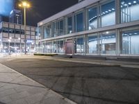 a stop sign that is on the corner of the road at night time near a building