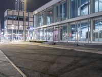 a stop sign that is on the corner of the road at night time near a building