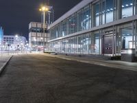 a stop sign that is on the corner of the road at night time near a building