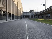 an empty street between two overpasses on a clear day with grass and flowers