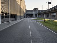 an empty street between two overpasses on a clear day with grass and flowers