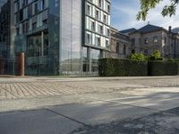 the empty street in front of a very modern building with high windows and a bike